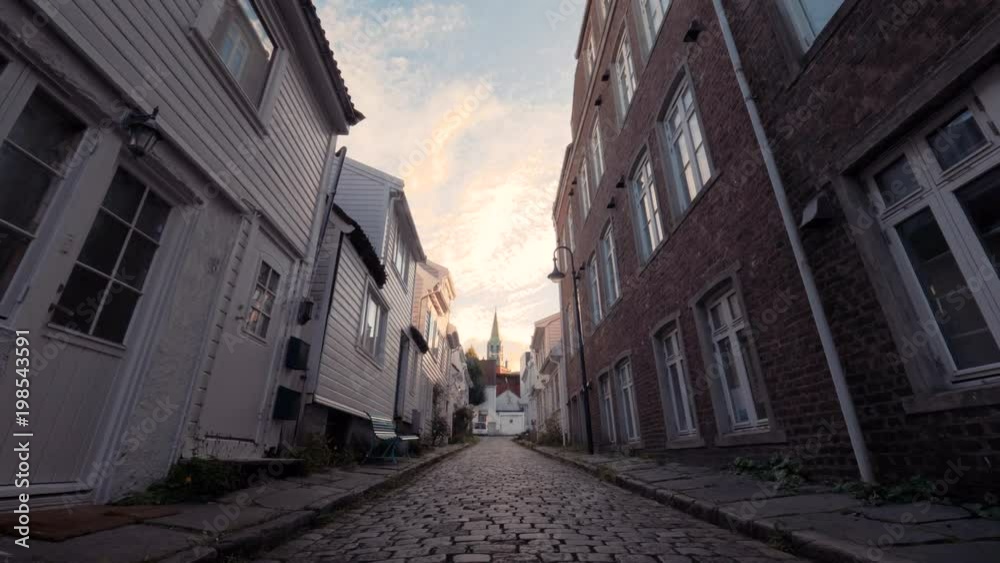 Walking in typical European street on paving stones, along small and big well-groomed houses, benches. Good weather at sunset. Cozy streets of villages in Norway. Lifestyle in suburbs and small towns. Walking in typical European street on paving stones, along small and big well-groomed houses, benches. Good weather at sunset. Cozy streets of villages in Norway. Lifestyle in suburbs and small towns.
