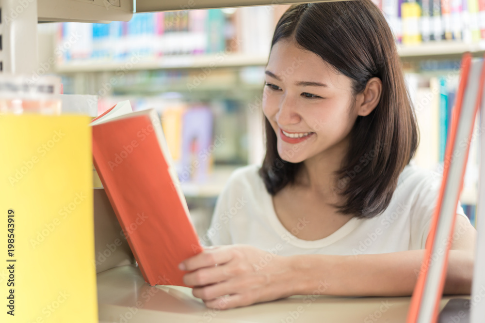 Asian student reading in the library at university. Student happy when she reading book.. Asian student reading in the library at university. Student happy when she reading book..