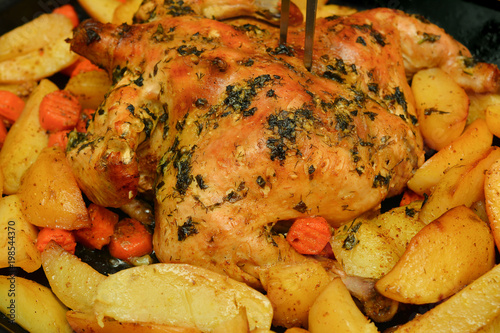 Baked in the oven chicken with potatoes, carrots, herbs and spices.