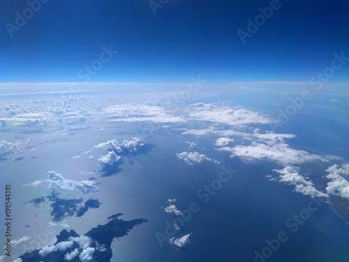 aerial view of bright blue sea and sky with white clouds casting shadows