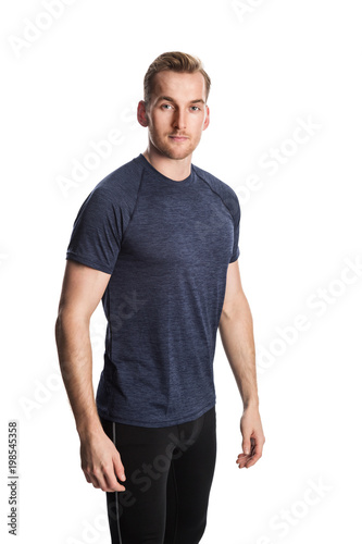 Blonde man wearing workout clothing standing against a white background staring at camera.