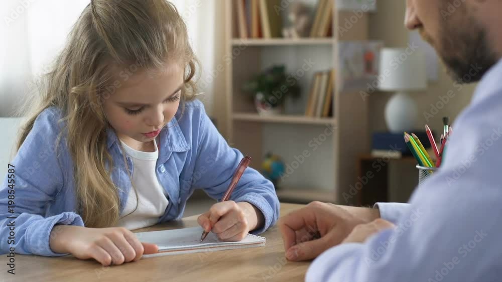 Girl writing exercise notebook with tutor help, additional education, assistance Girl writing exercise notebook with tutor help, additional education, assistance