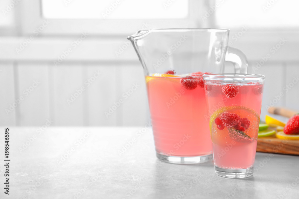Jug and glass of fresh lemonade with berries on table Jug and glass of fresh lemonade with berries on table