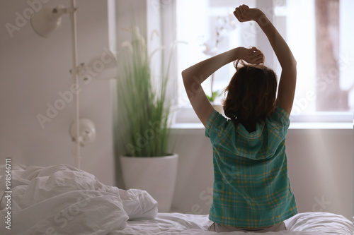 Photography Morning of woman stretching while sitting on bed