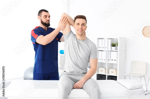 Physiotherapist working with young male patient in clinic