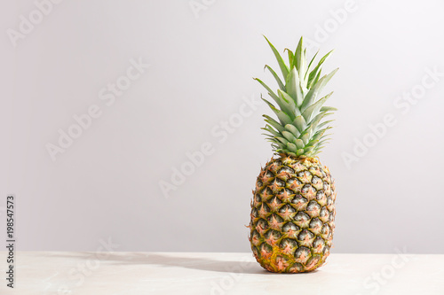 Fresh pineapple on table against grey wall