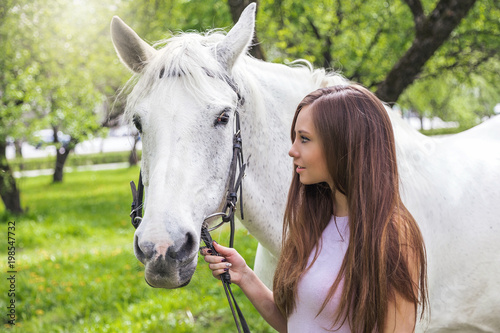 красивая молодая женщина в весеннем парке с белой лошадью 
