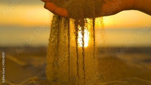 Canvas-taulu CLOSE UP: Small particles of dry sand fall between gentle unknown female fingers