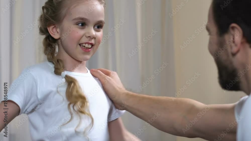 Small girl boxing father and showing success gesture, sport child development Small girl boxing father and showing success gesture, sport child development