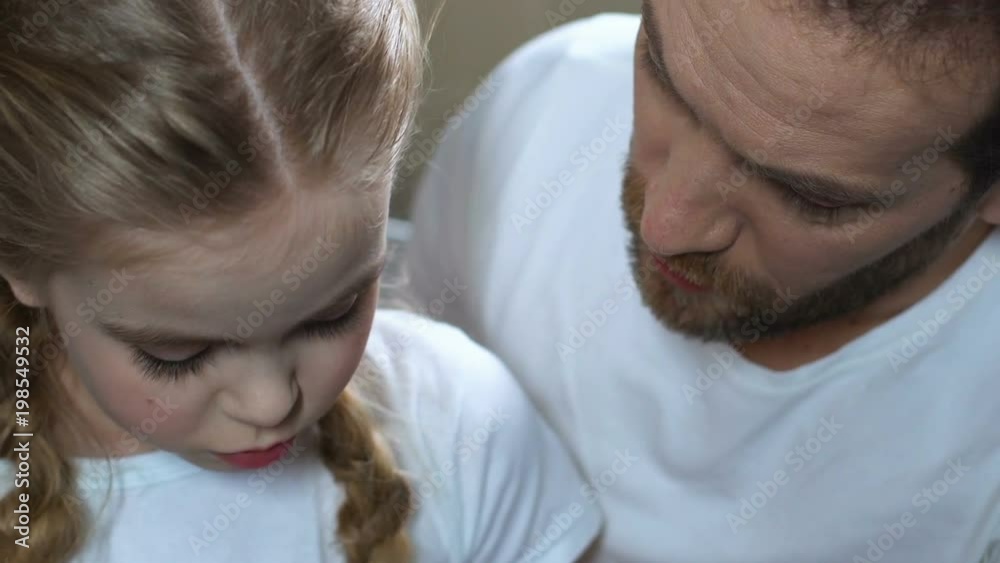 Loving father calming down sad daughter, spending time together, parent love