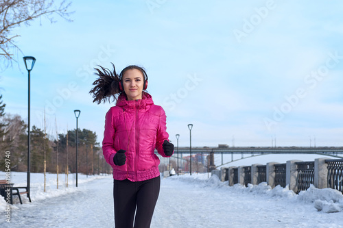 Running athlete woman sprinting during winter training outside in cold snow weather. Close up showing speed and movement. photo