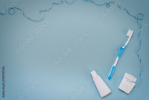Dental floss, toothbrush and toothpaste on a blue background