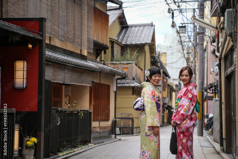 Women in traditional dress that call kimono, are walking on the stone pavement in culture street at Gion, Kyoto, Japan.