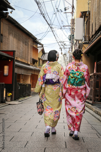 Women in traditional dress that call kimono, are walking on the stone pavement in culture street at Gion, Kyoto, Japan.