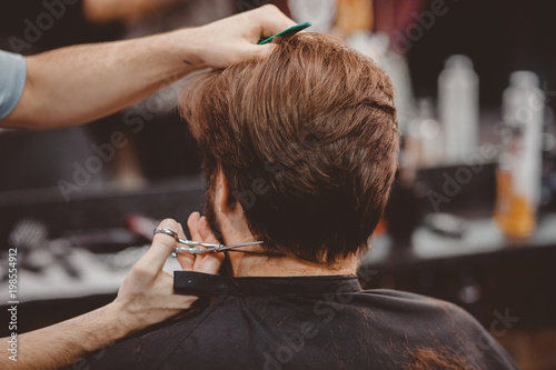 Barbershop. Close-up of man haircut, master does the hair styling in barber shop