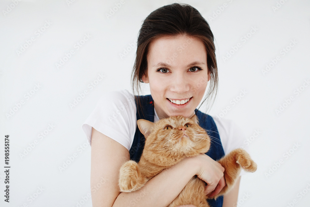 Young cute woman holding a red fluffy cat in her arms and smiling Young cute woman holding a red fluffy cat in her arms and smiling