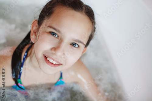 Young little cute teenager girl is sitting in the therapeutic whirlpool bath