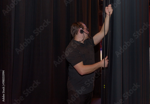 male theater technician  pulling a curtain pulley
