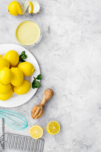 Cook lemon curd. Sweet cream in bowl, fruits, kitchen utensils on grey background top view copy space