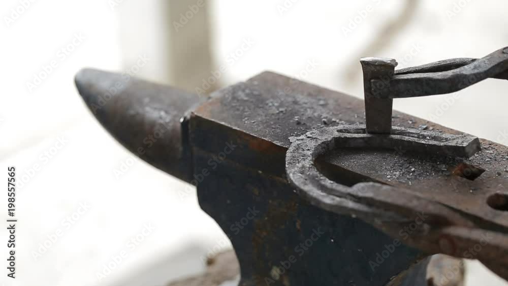 A blacksmith pounding a hammer on red-hot horseshoe on the anvil. A blacksmith pounding a hammer on red-hot horseshoe on the anvil.