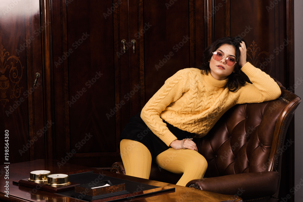 Portrait of a stunning fashionable model sitting in a chair in retro style