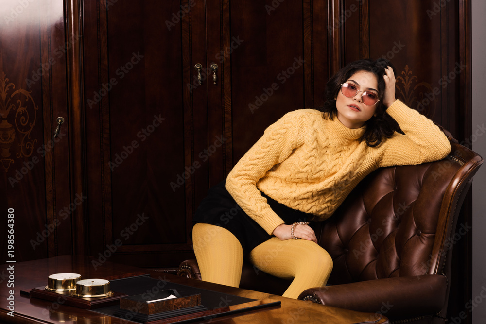 Obraz premium Portrait of a stunning fashionable model sitting in a chair in retro style