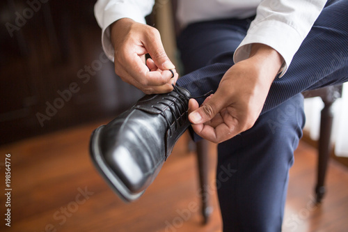 Man wears black shiny shoes in morning wedding preparations or business work