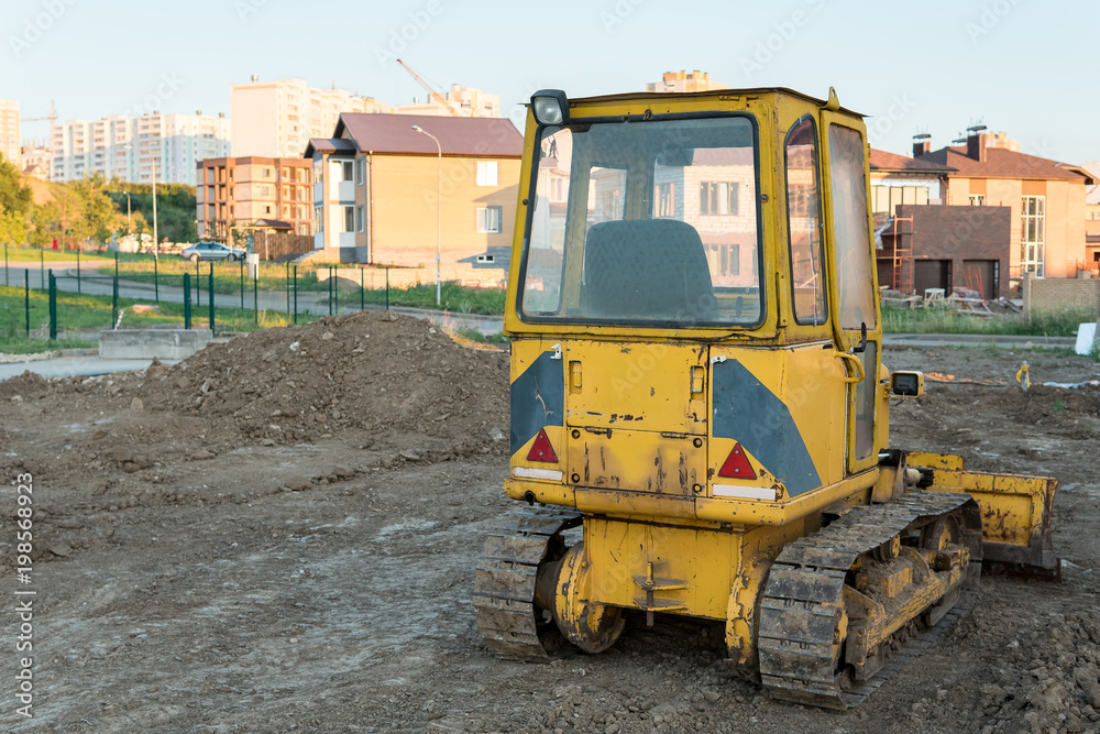 back view of small yellow bulldozer on the background of new private houses, back view of small yellow bulldozer on the background of new private houses,
