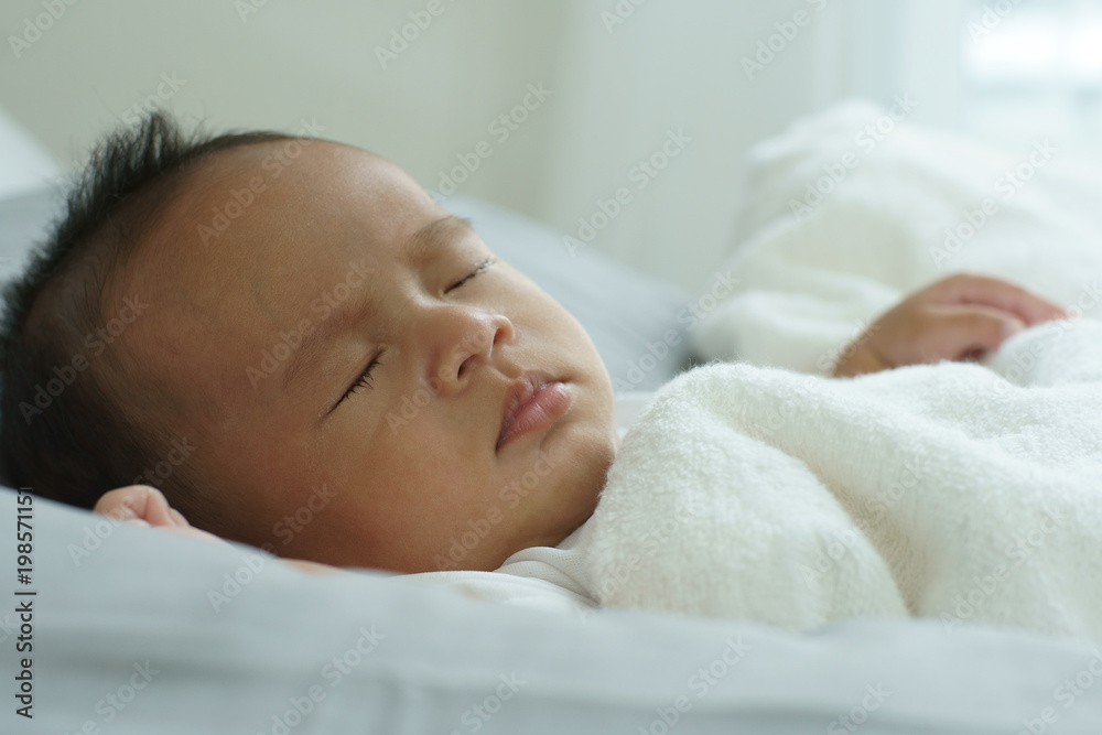 Young beautiful Asian mother caring and playing with her baby in the bedroom on a bright morning sunshine Young beautiful Asian mother caring and playing with her baby in the bedroom on a bright morning sunshine