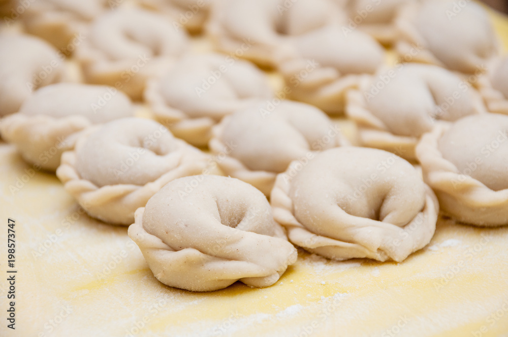 Untreated only molded dumplings lie in rows on a yellow silicone board diagonally