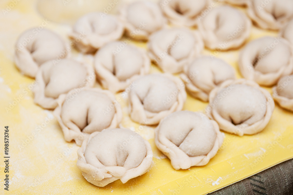Untreated only molded dumplings lie in rows on a yellow silicone board diagonally Untreated only molded dumplings lie in rows on a yellow silicone board diagonally