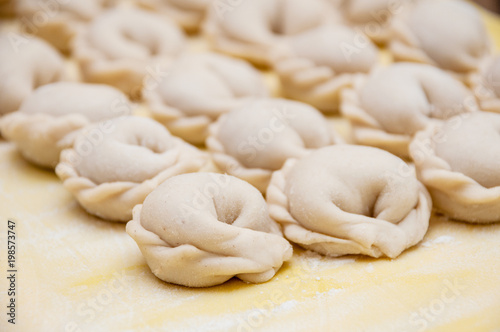 Untreated only molded dumplings lie in rows on a yellow silicone board diagonally