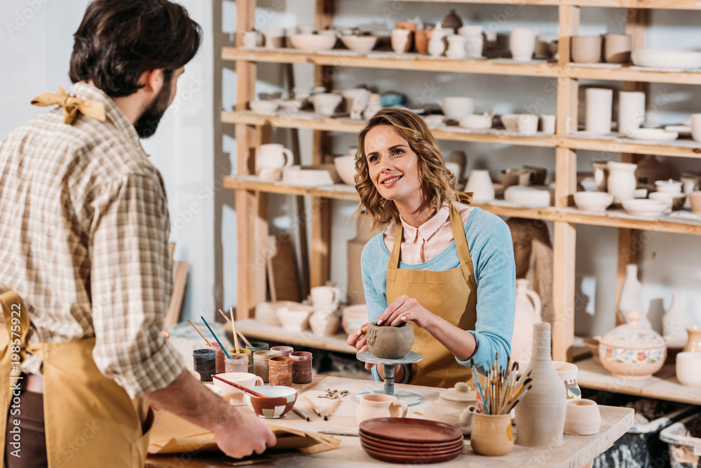 man with papers and female potter with ceramics in workshop man with papers and female potter with ceramics in workshop