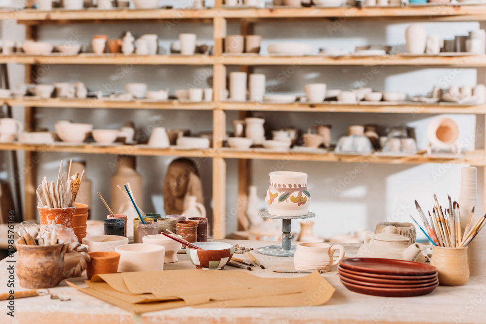 brushes, paints and wooden shelves with ceramics in pottery workshop brushes, paints and wooden shelves with ceramics in pottery workshop