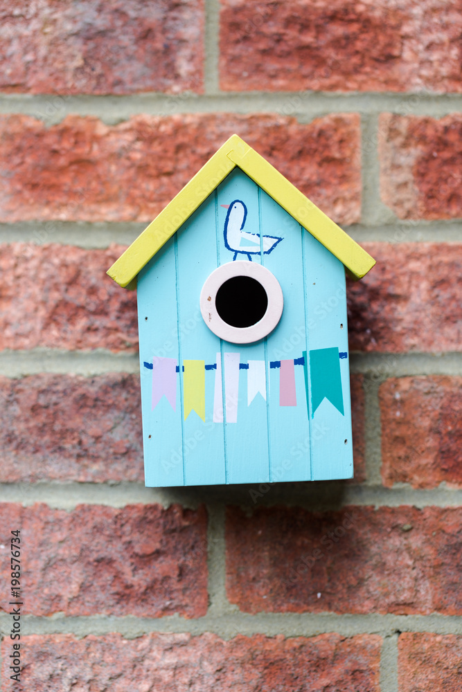Blue small cue wooden bird house hanged on brick wall Blue small cue wooden bird house hanged on brick wall
