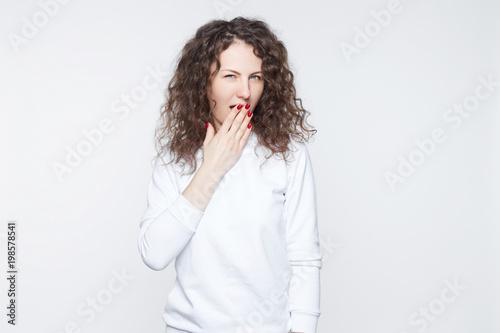 Omg! Surprised funny Caucasian woman covering mouth with hand, opening mouth widely and popping eyes out in surprise looking at camera, shocked with astonishing news or gossip. Body language concept.