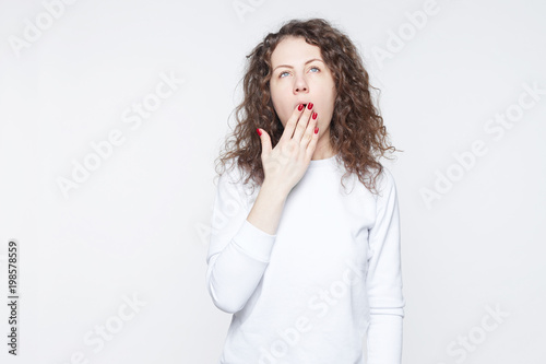 Headshot of young bored pretty woman, yawning isolated on light background. Facial expressions, feelings, body language. College student after long hours of doing homework, chronic fatigue of exams.