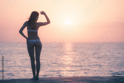 Silhouette of woman watching sunrise over ocean horizon © Nickolay Khoroshkov