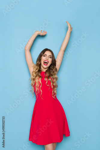 Happy Young Woman In Red Dress Is Shouting With Arms Raised