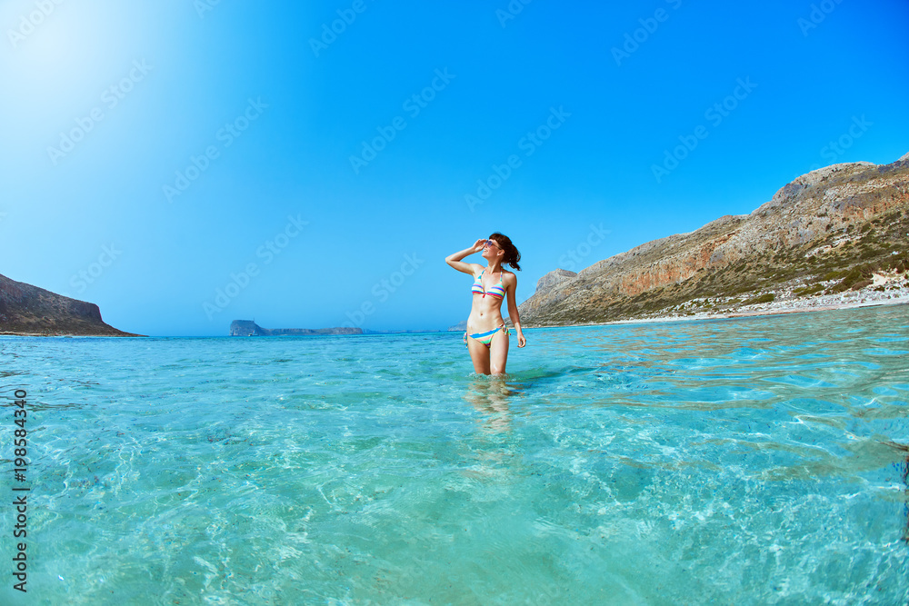 beautiful sexy woman dressed in bikini standing on the beach in the sea. vacation and travel photography concept