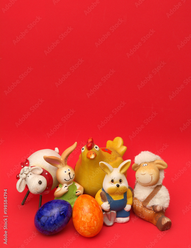 Osterfiguren Schafe, Hasen, Küken und bunte Ostereier vor rotem Hintergrund. Hochformat. Gruppenfoto. Osterfiguren Schafe, Hasen, Küken und bunte Ostereier vor rotem Hintergrund. Hochformat. Gruppenfoto.