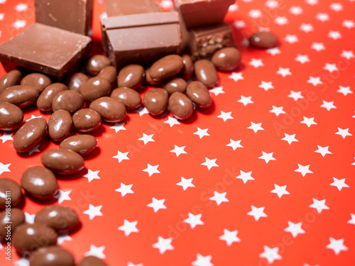 Pieces of chocolates on red background photo