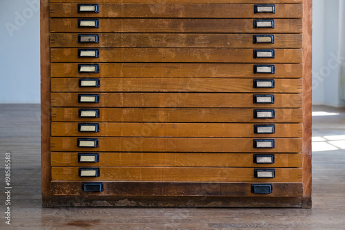 old vintage wooden cabinet with drawers with handles and plates, might have been used for large plans, maps or other typographic means