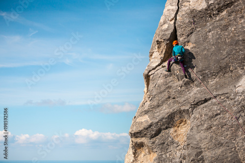 Girl in helmet climbs the rock.