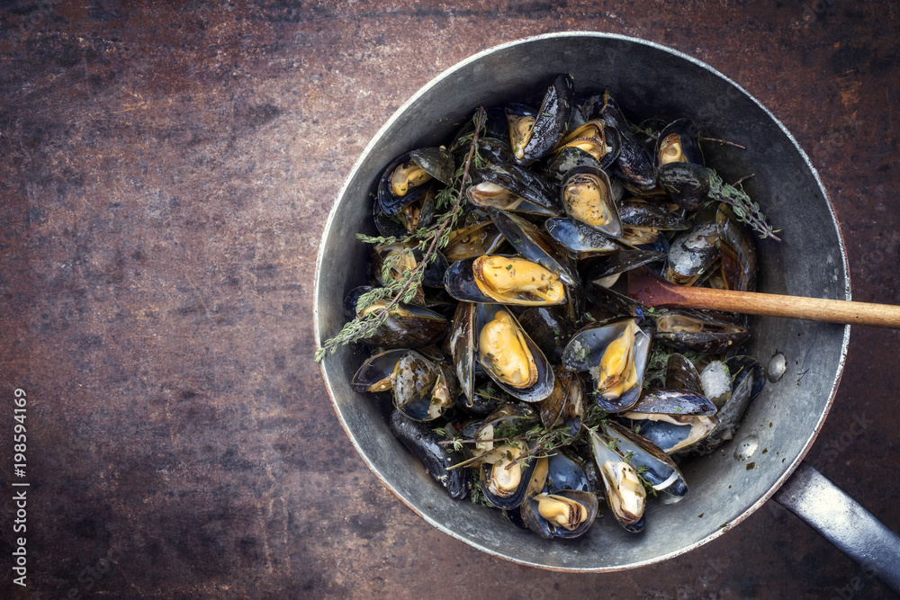 Traditional barbecue Italian blue mussel with rosemary as top view in a casserole Traditional barbecue Italian blue mussel with rosemary as top view in a casserole