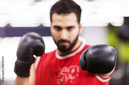 Bearded boxing man wears red shirt and black gloves in the ring © proimagecontent