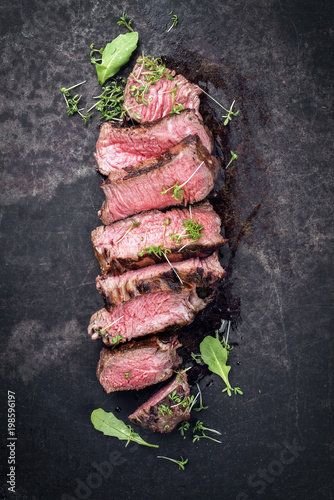 Barbecue wagyu point steak slices with lettuce and herbs as top view on a board with copy space