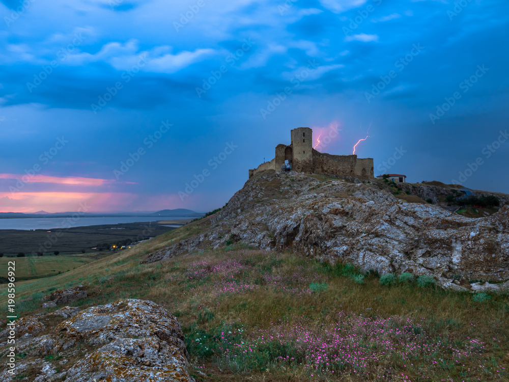 Thunderbolts,lightning on a cloudy evening blue sky over old Enisala stronghold,citadel, Dobrogea, Romania Thunderbolts,lightning on a cloudy evening blue sky over old Enisala stronghold,citadel, Dobrogea, Romania