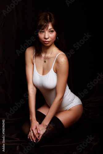 Pretty sexy curvy brunette in a white body on a black backgroung © Sergey