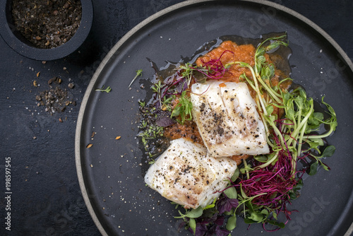 Steamed cod fish filet with lettuce as top view on a plate with copy space left photo